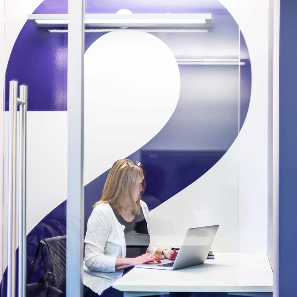 Glass door entrance to Mosaic CoWork with textured wall and geometric floor pattern.