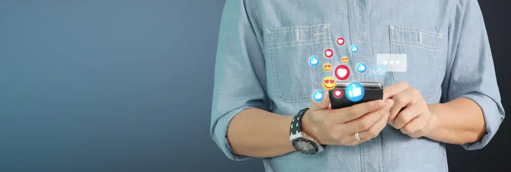 Person holding a smartphone with social media reaction icons.
